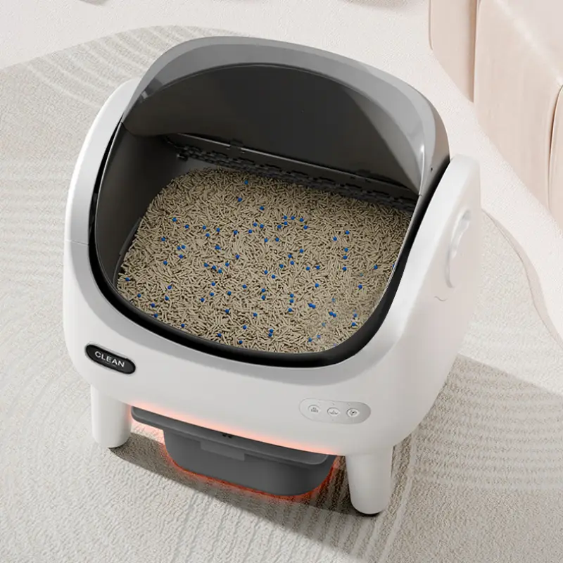 Top-down view of an open-style smart self-clean cat litter box filled with cat litter in a bright modern pet home interior space